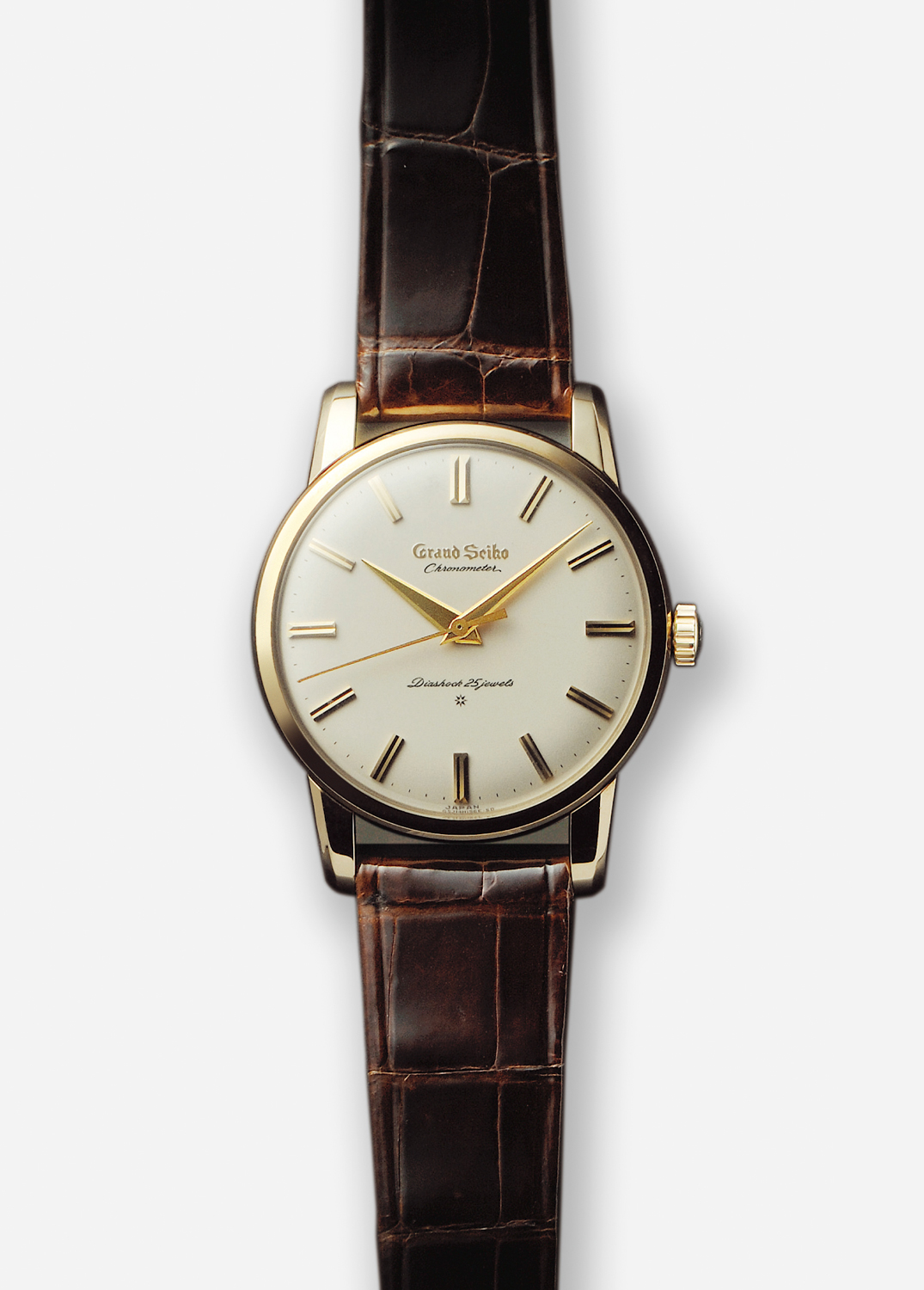 First grand Seiko in yellow gold with a brown strap on light backdrop.