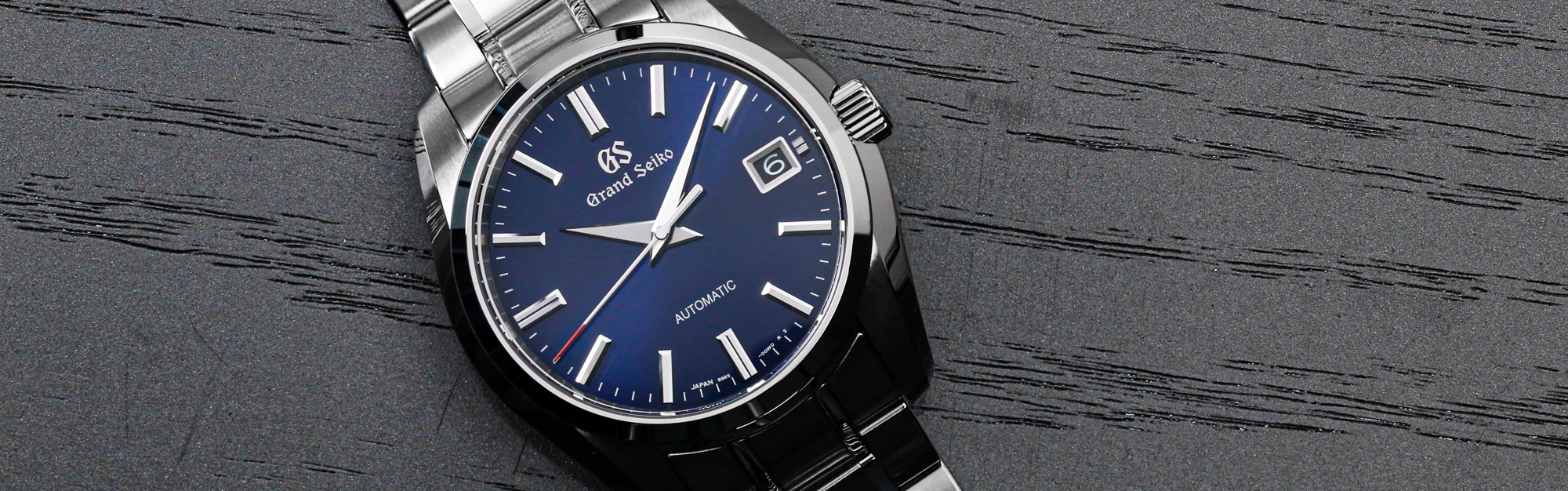 Grand Seiko SBGR321 wristwatch with a blue dial and red accents on a tabletop.