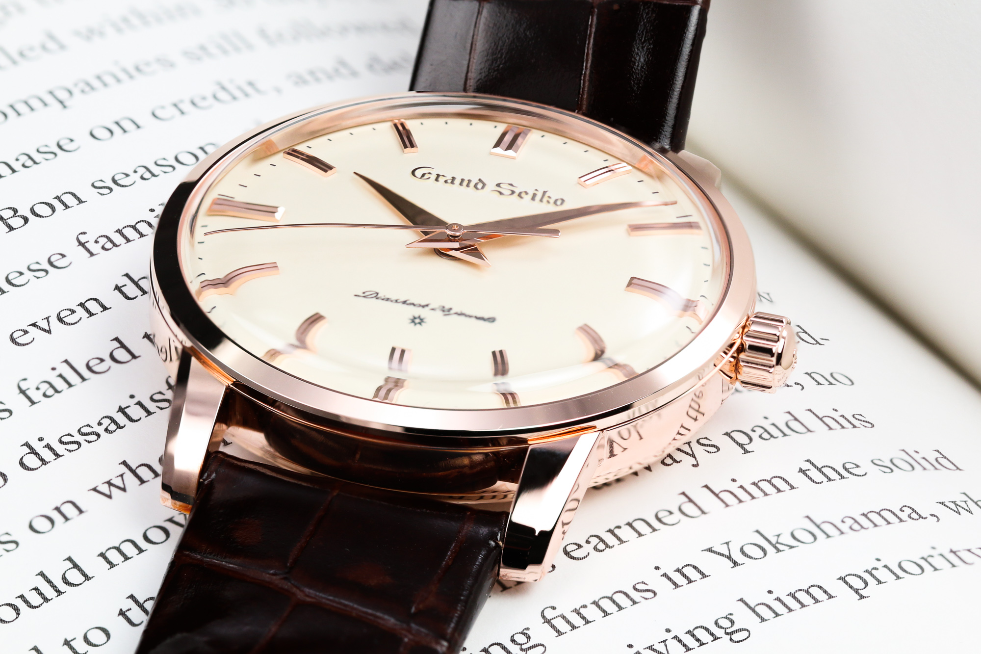 Grand Seiko SBGW260 light dial and gold case on a book.