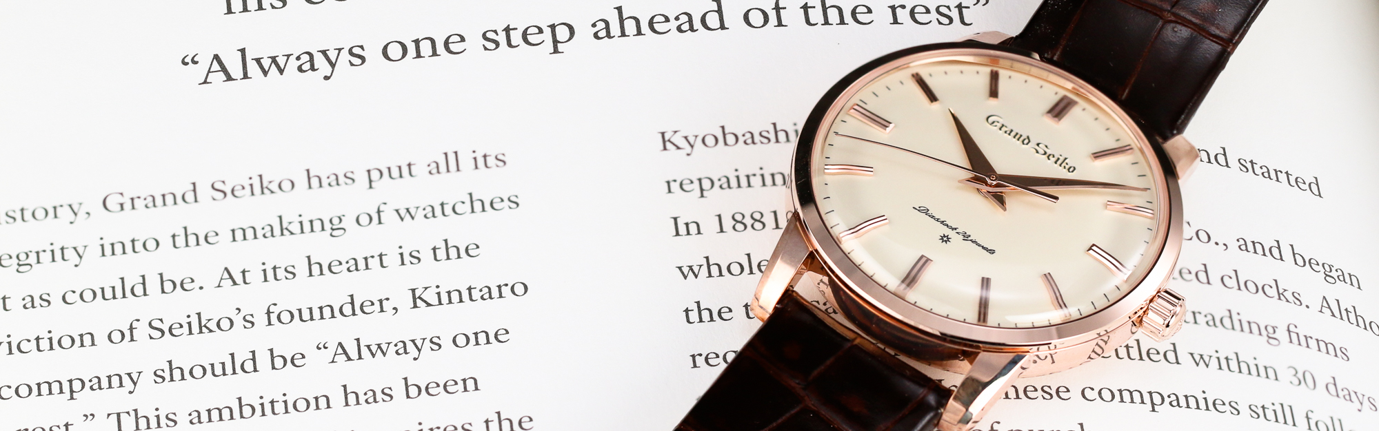 Grand Seiko SBGW260 gold case light dial wristwatch on a book.