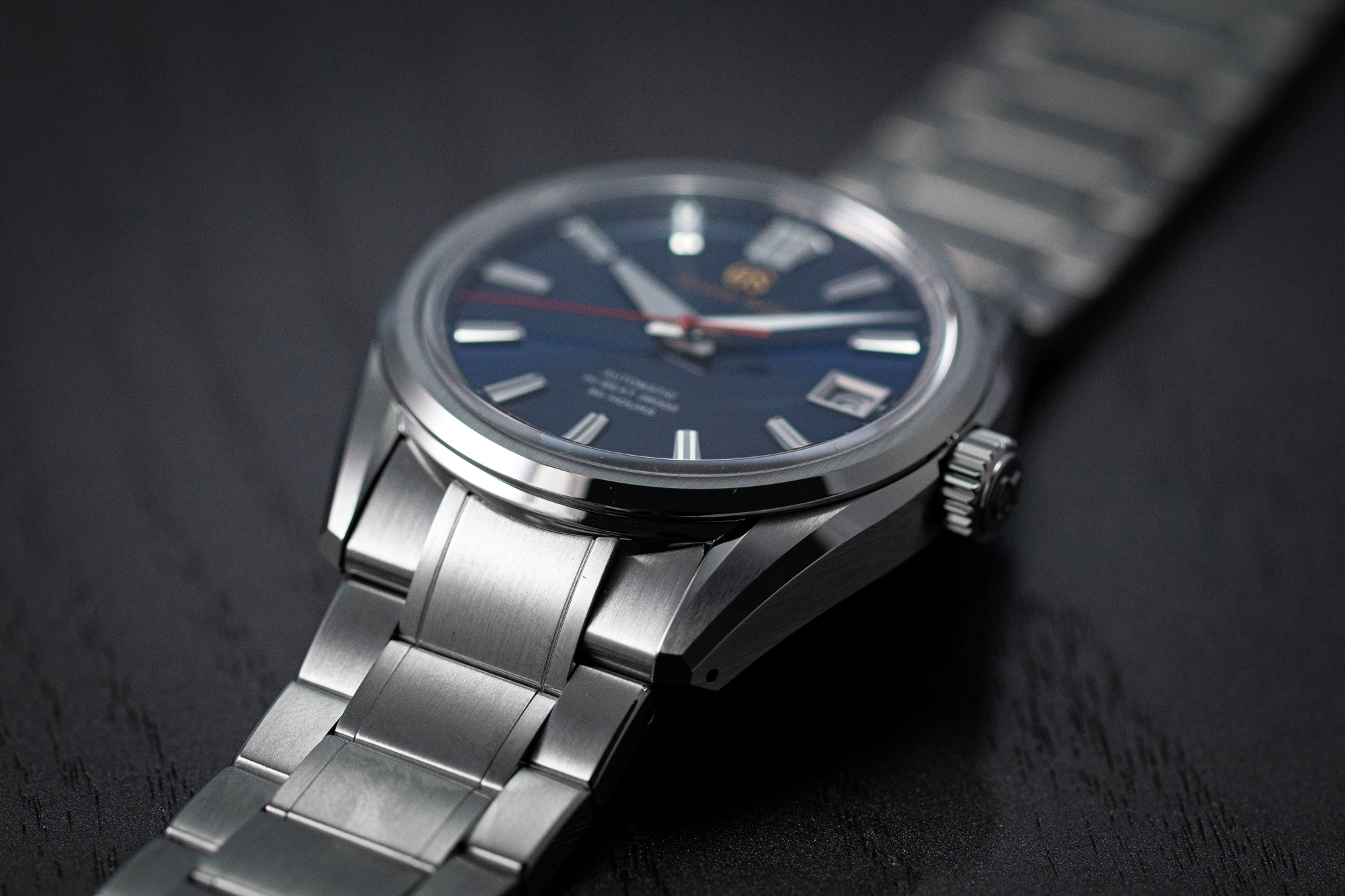 Grand Seiko SLGH003 wristwatch with a blue dial and red accents on a tabletop.