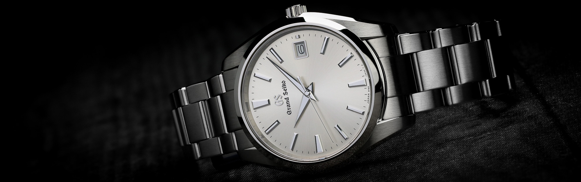 Grand Seiko SBGP009 white dial wristwatch on its side.