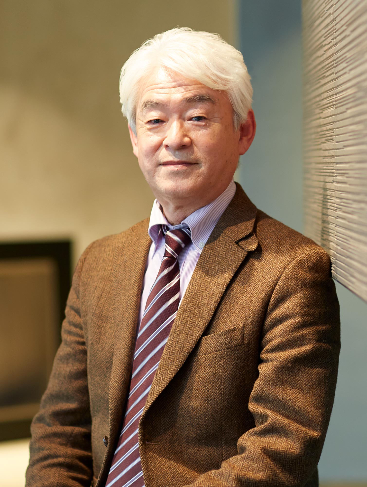 Portrait of Nobuhiro Kosugi wearing a brown tweed suit.